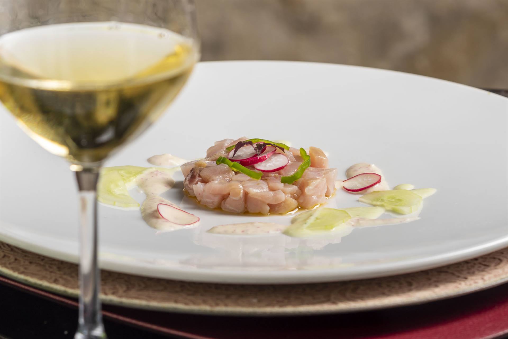Tavola di un ristorante elegante: crudo di pesce e calice di vino